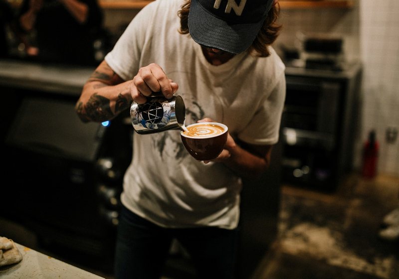 Barista pouring latte art into a coffee cup