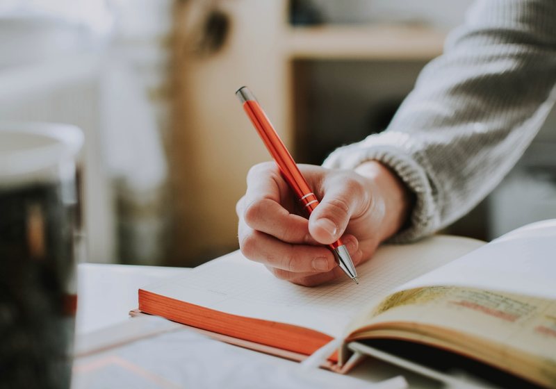 Hand writing notes in a notebook while deciding