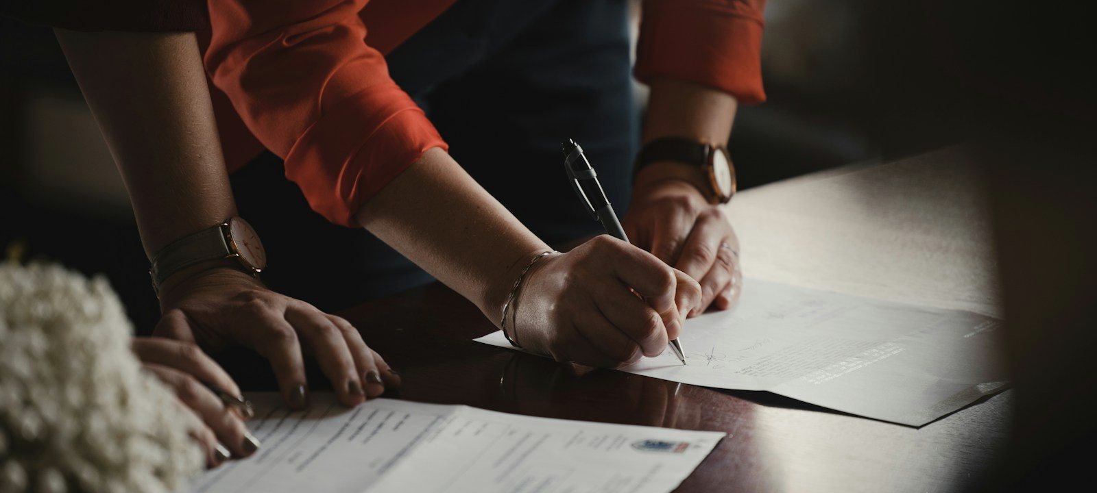Two people signing a document together at a desk