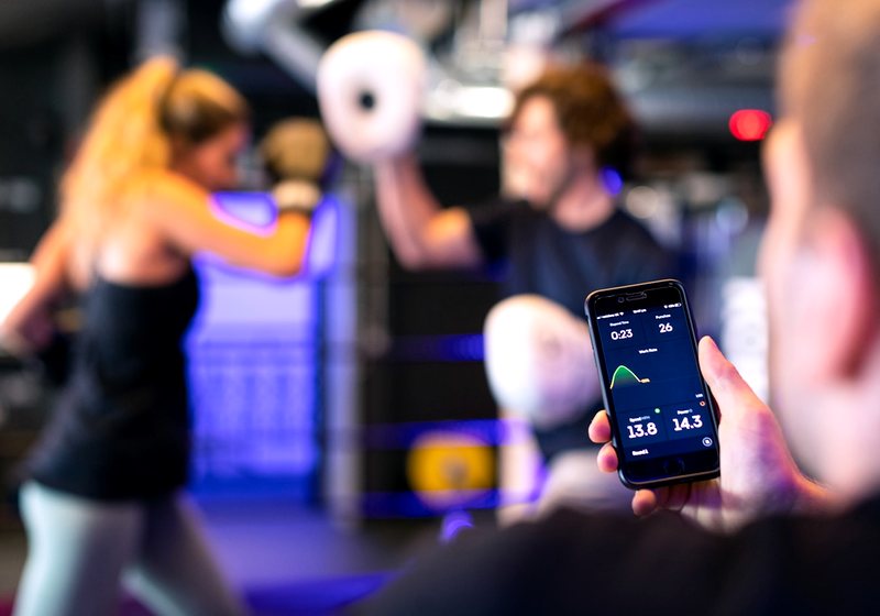 Person checking workout stats on a phone in a gym