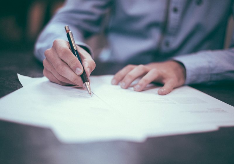 Person signing a legal document with a pen