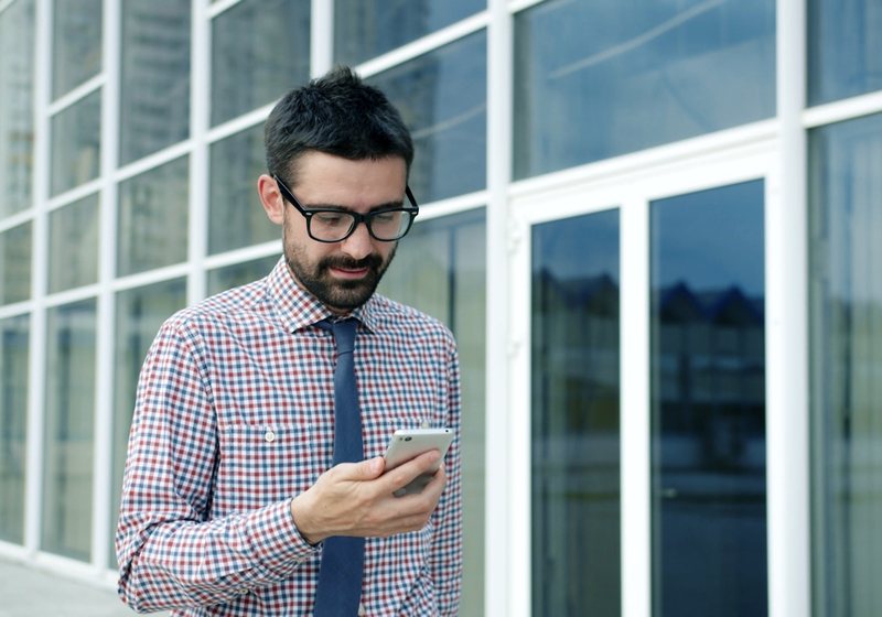 Man checking his phone outside an office building