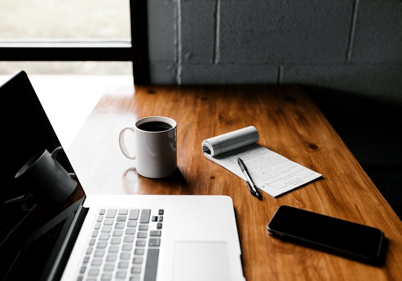 Laptop and smartphone side by side on a wooden desk