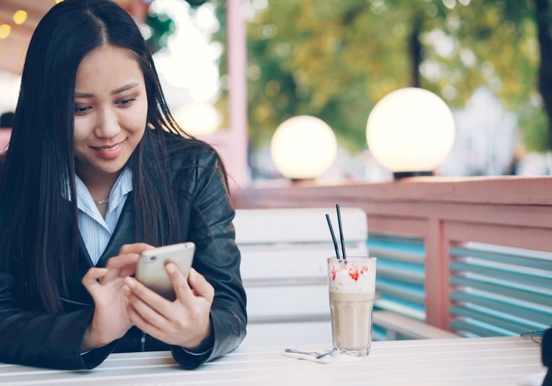Woman checking a phone at an outdoor café table
