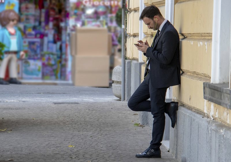 Man checking his phone while waiting on a street
