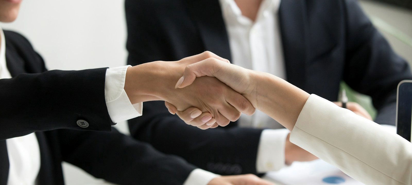 Two people shaking hands over a business agreement