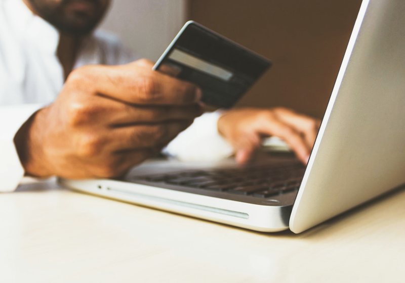 Person holding a card while using a laptop for an online payment