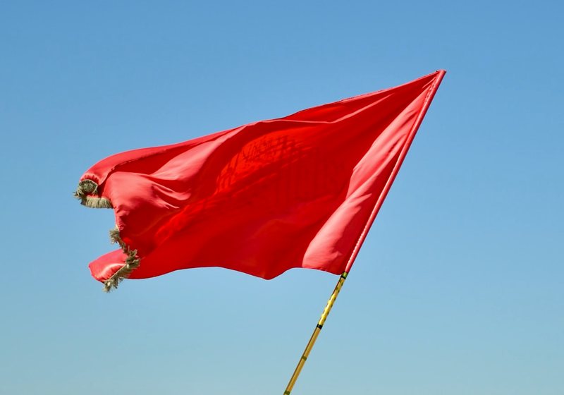 A red flag waving against a blue sky